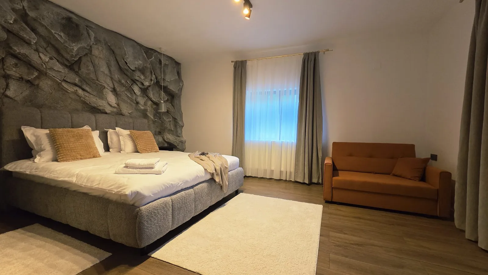 Odaia stâncii: patul matrimonial, peretele de rocă și canapeaua extensibilă de lângă fereastră