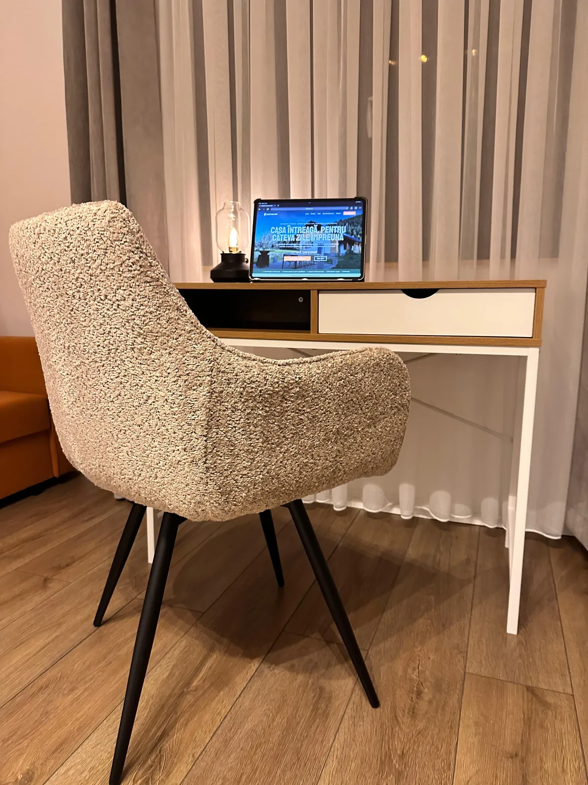 Biroul din Odaia stâncii: masa de lucru cu sertar, scaunul tapițat și laptopul, lângă fereastră