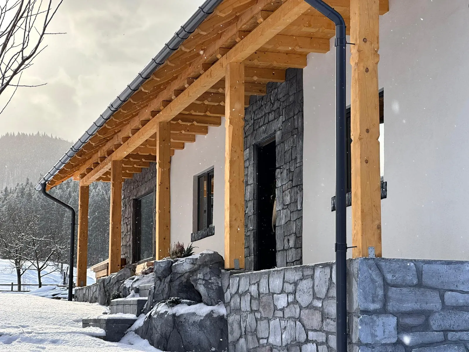 Casa Artcetera Lodge iarna, cu prispa de lemn și zăpada din curte